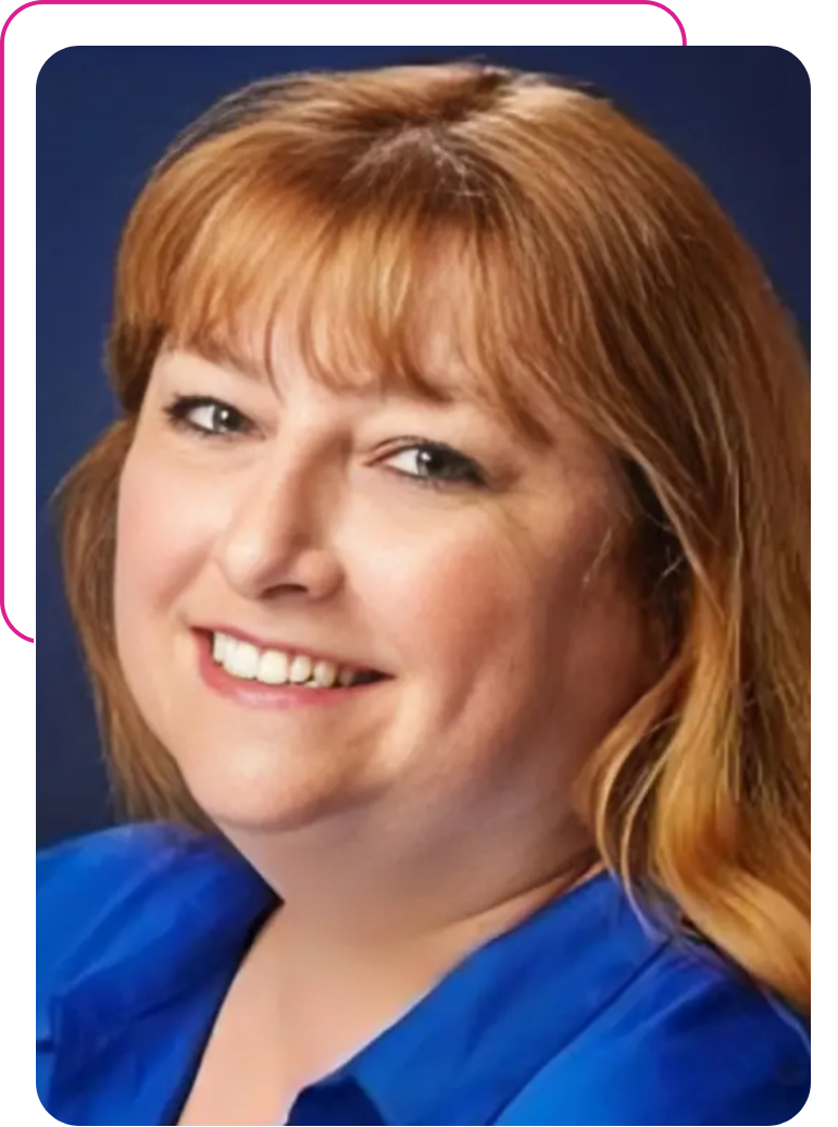 A woman with red hair and blue shirt smiling.